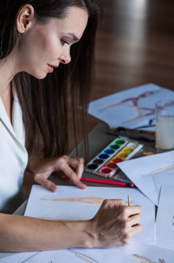 Kadın suluboya ile mayo ve iç çamaşırı çiziyor.