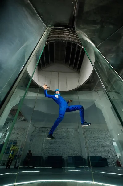 stock image A man in overalls and a protective helmet enjoys flying in a wind tunnel. Free fall simulator.