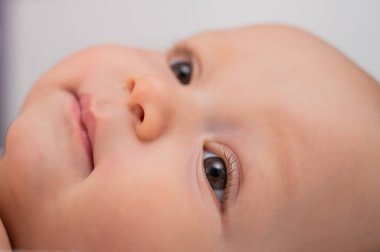 Yatakta uzanmış kahverengi gözlü bebek portresi.
