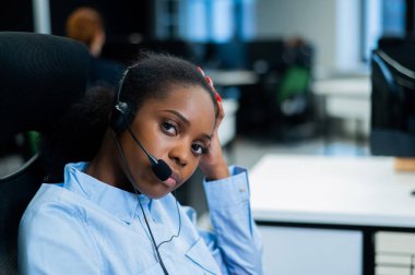 Afrikalı genç bir kadın kulaklıkla bir müşteriyle konuşuyor. Çağrı merkezinin kadın çalışanı