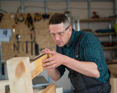 Marangoz atölyedeki tahtaları ölçer.