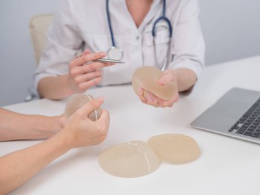 Caucasian woman and plastic surgeon touching and choosing breast implants