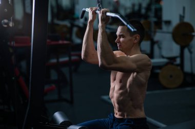 A man does a chest pulldown in the gym