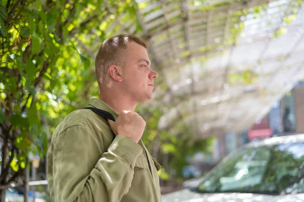Young caucasian man with hearing device walking outdoors