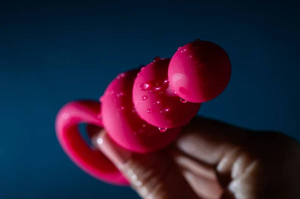 在蓝色背景的水滴中 女人拿着粉色的肛珠 性玩具卫生概念 — 图库照片