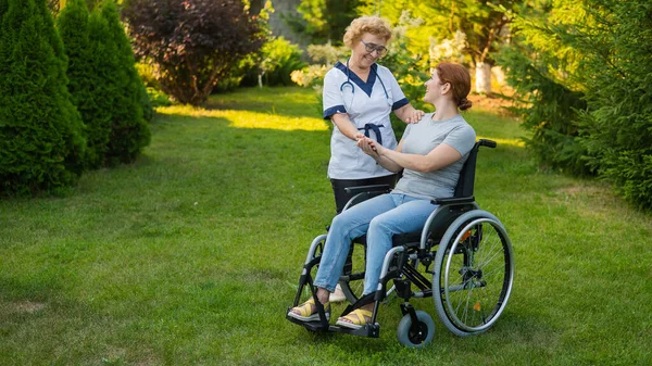 Elderly Female Nurse Walks Middle Aged Woman Wheelchair Park — Stockfoto