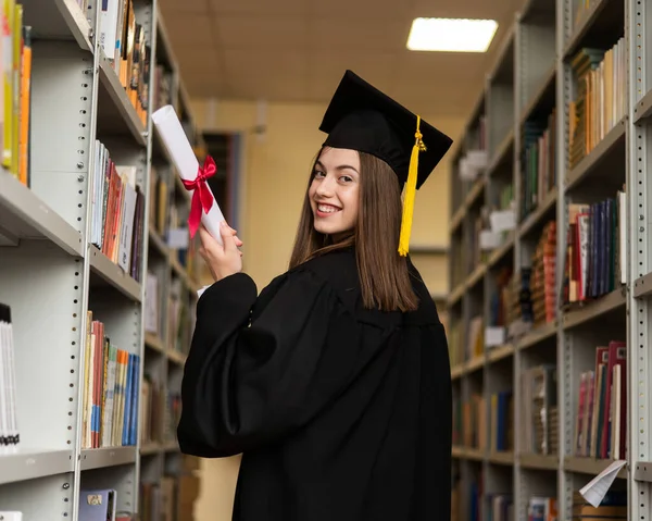 Счастливая Молодая Женщина Выпускном Платье Держит Диплом Библиотеке — стоковое фото