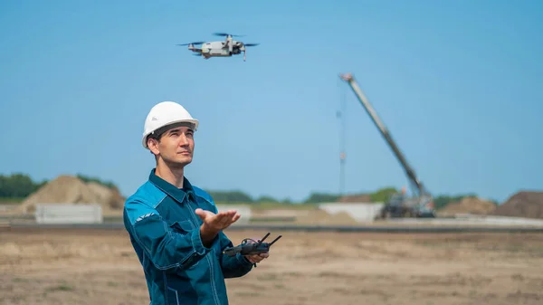 Homem Capacete Macacão Controla Drone Num Estaleiro Construtor Realiza Supervisão — Fotografia de Stock