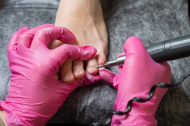 Usta müşteriye donanım pedikürü yapıyor. Kütikül tedavisi