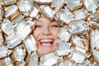 The face of a Caucasian woman surrounded by candy wrappers