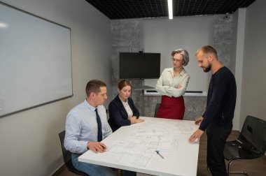 The female boss evaluates the work of subordinates. Designers engineers at a meeting