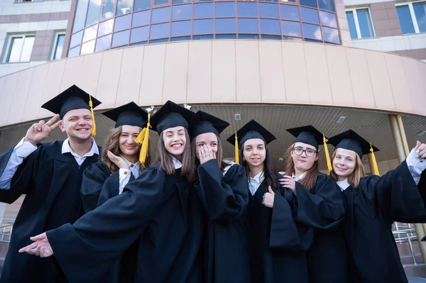 Счастливые Студенты Выпускном Платье Стоят Ряд Фоне Университета — стоковое фото