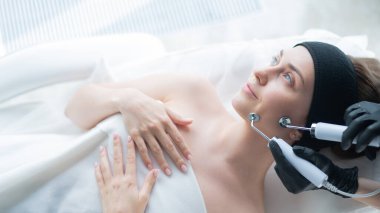 Genç beyaz kadın mikro akım terapi prosedürü uyguluyor. Güzellik bürosu