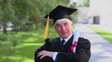 Mezuniyet elbisesi giymiş ve elinde diplomasıyla yaşlı bir adamın portresi.