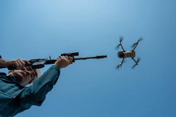Człowiek Celuje Karabinu Latającego Drona Przeciwko Błękitnemu Niebu — Zdjęcie stockowe