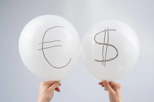 Woman holding two white balloons with dollar and euro symbols