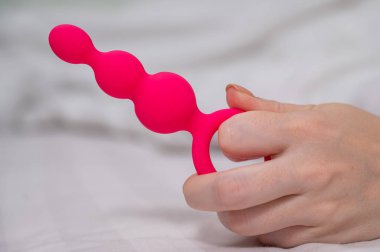 Yatakta uzanmış pembe anal boncuklu bir kadının yakın çekimi.