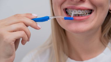 Beyaz kadın diş teli kullanarak dişlerini temizliyor. Kesilmiş portre