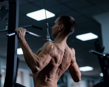 A man does a chest pulldown in the gym