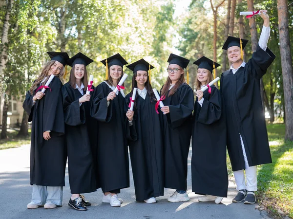 Ряд Молодых Студентов Выпускных Платьях Открытом Воздухе Демонстрирующих Свои Дипломы — стоковое фото