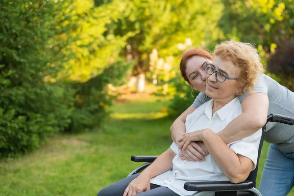 Caucasian Woman Hugging Elderly Mother Sitting Wheelchair Walk Outdoors — Stock Photo, Image
