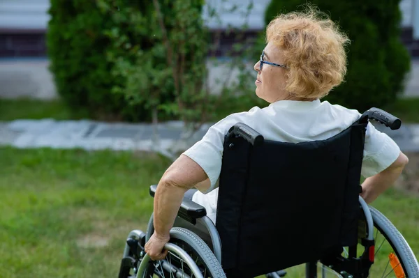 一个安静的老年妇女坐在轮椅上散步 — 图库照片