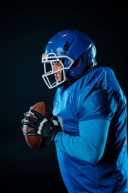 Siyah arka planda Amerikan futbolu için mavi üniformalı bir adamın portresi.