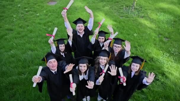 Vista Superior Grupo Graduados Con Túnicas Mostrando Diploma Estudiante Mayor — Vídeo de stock