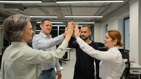 Four co-workers give a high five in the office