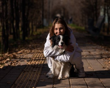 Sonbahar parkında sınır köpeğini kucaklayan beyaz bir kadın. Köpekli bir kızın portresi.