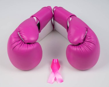 Pink boxing gloves and a pink silk ribbon on a white background. Breast cancer concept clipart