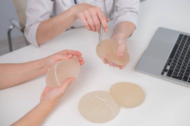 Caucasian woman and plastic surgeon touching and choosing breast implants