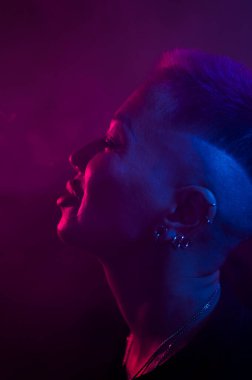 Kısa saçlı, neon ışıkta sigara içen Asyalı kadın profili
