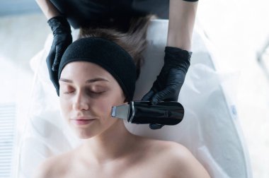 Ultrasonik temizlik prosedüründeki bir kadının üst görüntüsü. Donanım kozmetolojisi