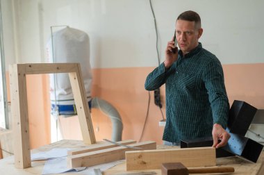 Atölyede telefonla konuşan beyaz bir adamın portresi.