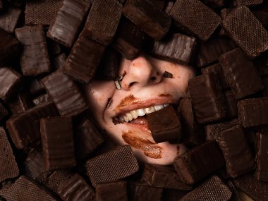 The face of a caucasian woman surrounded by sweets. The girl is smeared in sweets