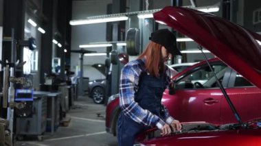 Kadın oto tamircisi bir fındığı söküp yerine buji takıyor.