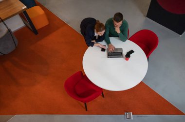 Yuvarlak masada dizüstü bilgisayarla çalışan kadın ve erkeğin üst görüntüsü