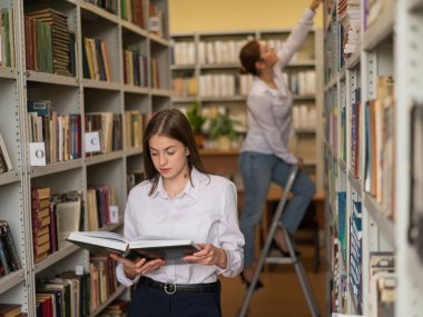 Halk kütüphanesinde iki genç kız öğrenci.
