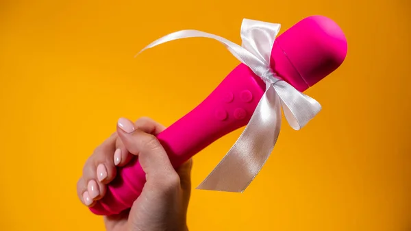 stock image Woman holding pink vibrator with white bow on orange background