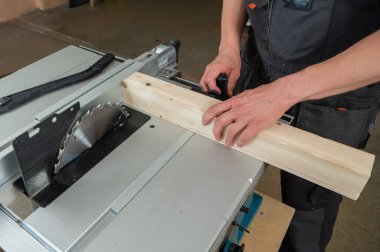 Dairesel bir makinede tahta kesen bir adamın yakın çekimi.