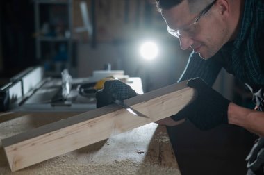 Marangoz atölyede çalışırken tahta bir tahta ölçer.