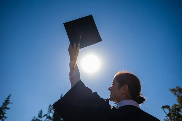 青い空に女が卒業キャップを投げつける — ストック写真