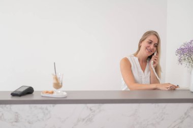 Güzellik salonunda resepsiyonist telefonda bir müşteriyle konuşuyor.