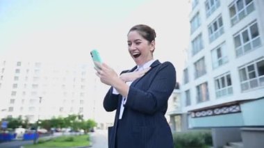 Video 360 derece. Kafkasyalı iş kadını akıllı telefona bakıyor ve dışarıda gülüyor.