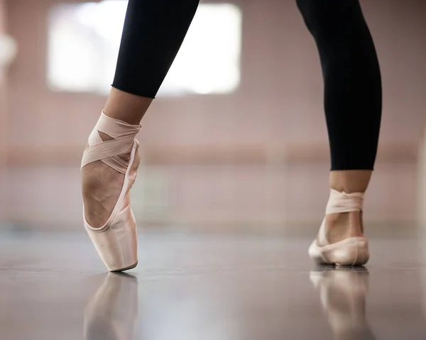 Close-up but ballerinas in pointe shoes in a dance class. The woman stands on one toe