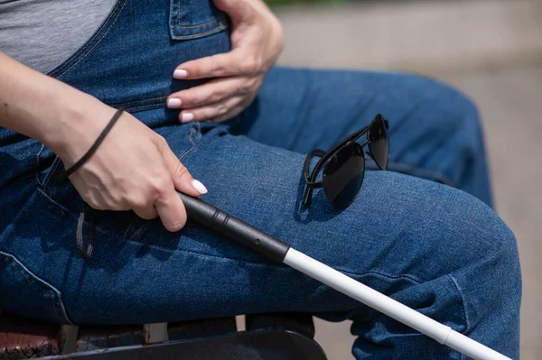 一个失明的孕妇坐在长椅上 手里拿着一根可折叠的触觉手杖 — 图库照片