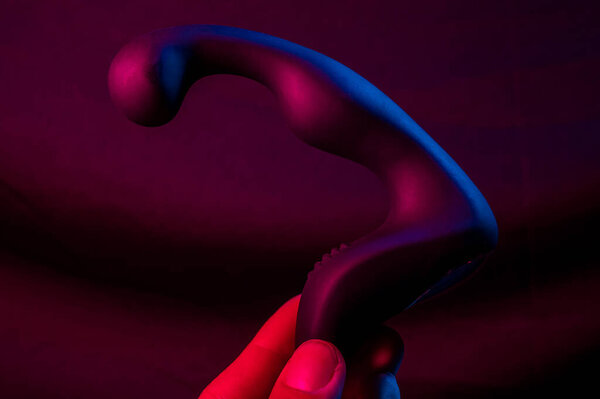 Man holding prostate stimulator in pink neon light
