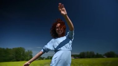 Mavi elbiseli beyaz bir kadın tarlada dans ediyor. Video 360 derece. Yavaş çekim
