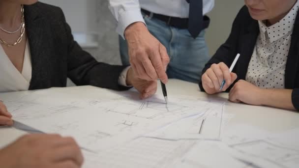 オフィスのテーブルの上に設計図を持つ4人の同僚の手のクローズアップ エンジニアや建築家のブレインストーミング — ストック動画